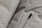 Close-up of a light gray puffer jacket showing a zippered pocket with a black zipper pull. UBR Jackets available at Sakks Menswear in Southampton.