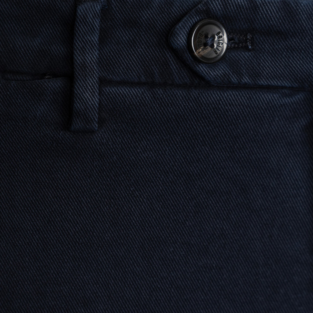 Close-up of dark navy blue denim fabric showing the texture, a belt loop, and a metal button with a visible G-100 brand logo. Briglia 1949 Trousers available at Sakks Menswear in Southampton.