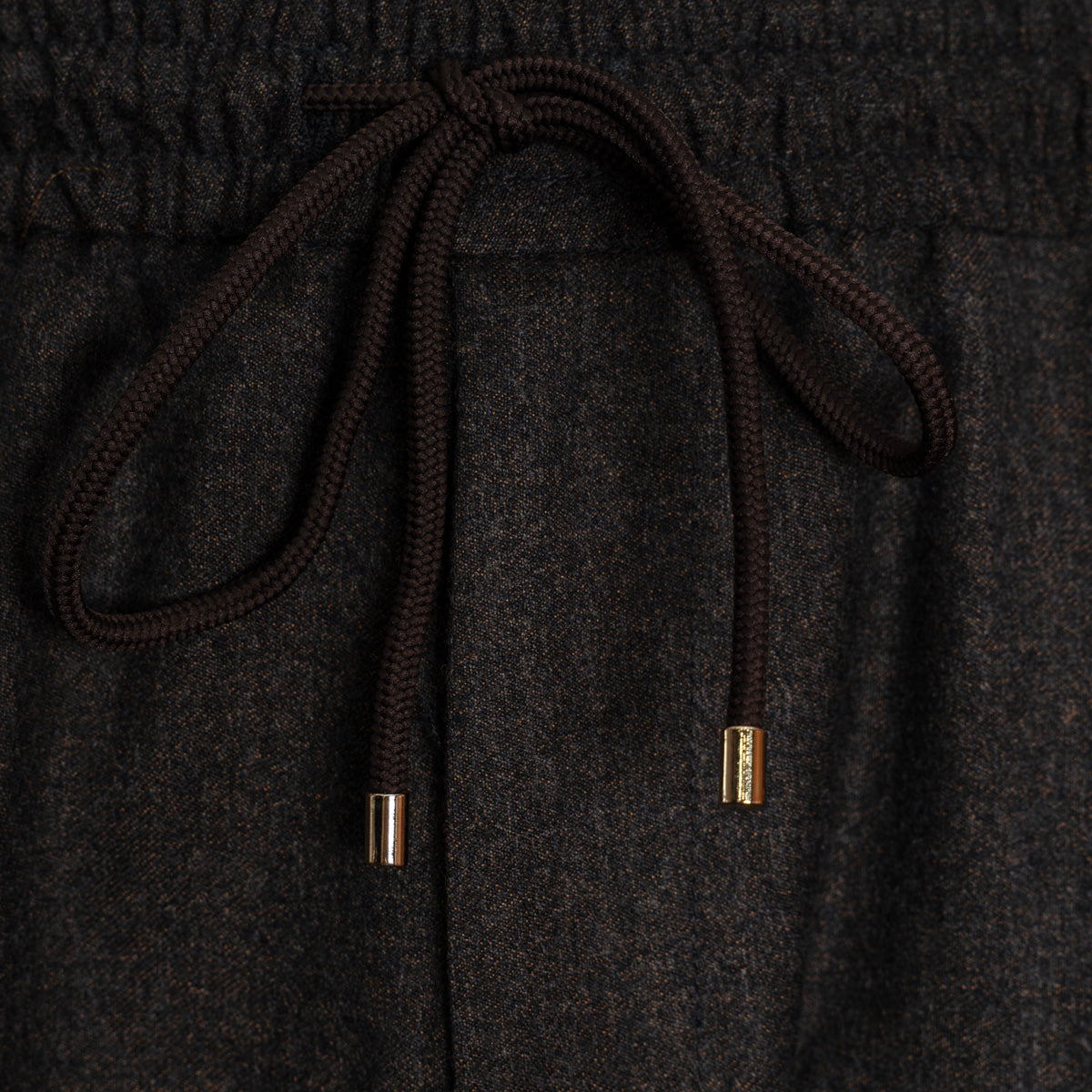 Close-up of dark charcoal gray textured fabric with a dark brown drawstring and small metallic gold end caps. Briglia 1949 Trousers available at Sakks Menswear in Southampton.