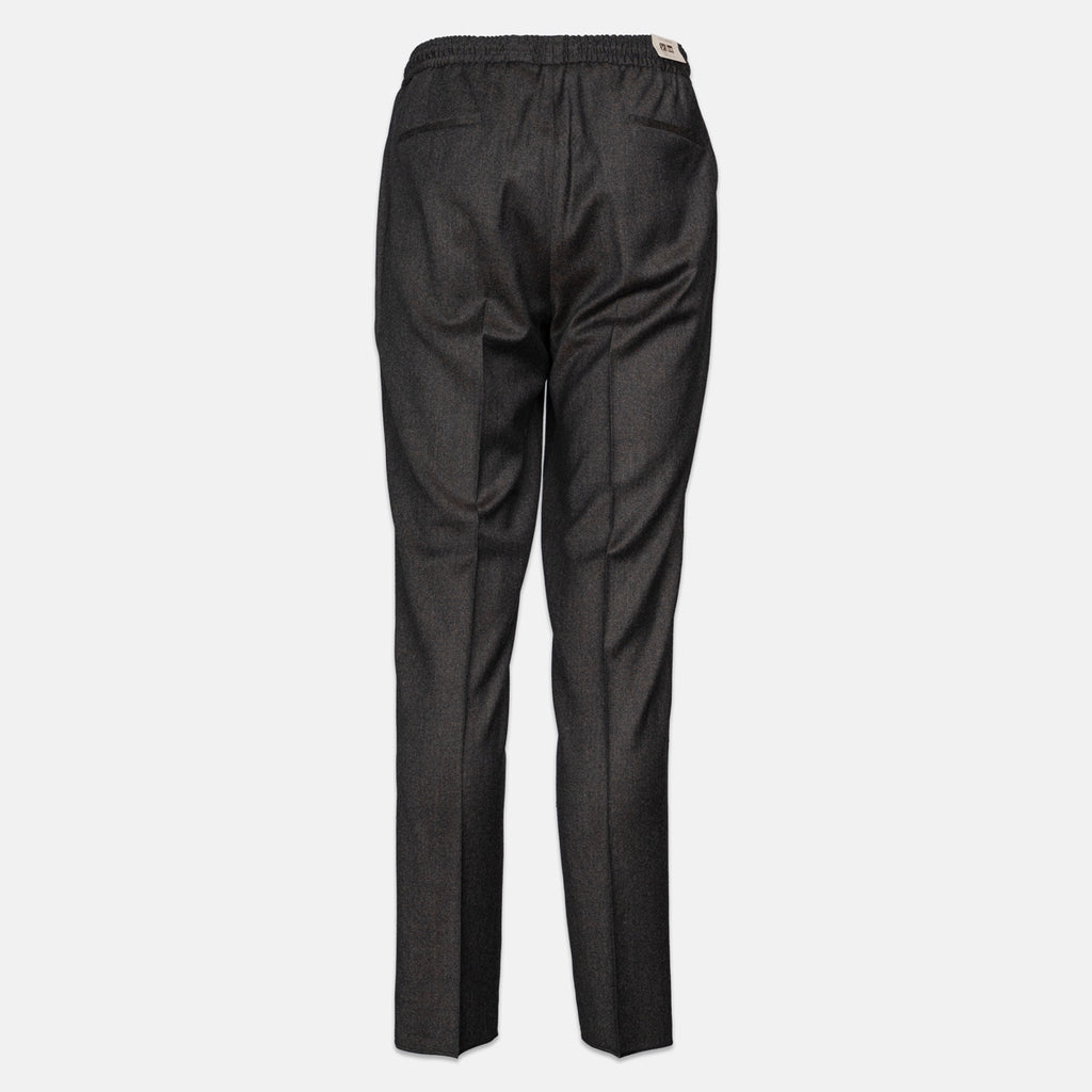 A pair of dark charcoal gray trousers shown from the back, featuring a subtle textured weave, a flat elastic waistband, and a small white brand label at the back waist. Briglia 1949 Trousers available at Sakks Menswear in Southampton.
