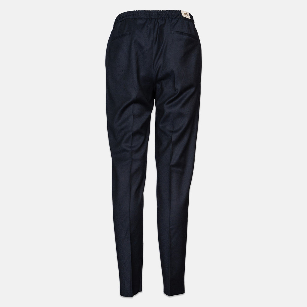 A pair of dark navy blue trousers shown from the back, featuring an elastic waistband and a small beige brand tag, set against a plain light gray background. Briglia 1949 Trousers available at Sakks Menswear in Southampton.
