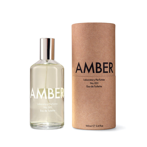 A bottle of Laboratory Perfumes No.001 Amber Eau de Toilette next to its brown kraft paper cylindrical packaging box on a white background. Laboratory Perfumes Amber available at Sakks Menswear in Southampton.