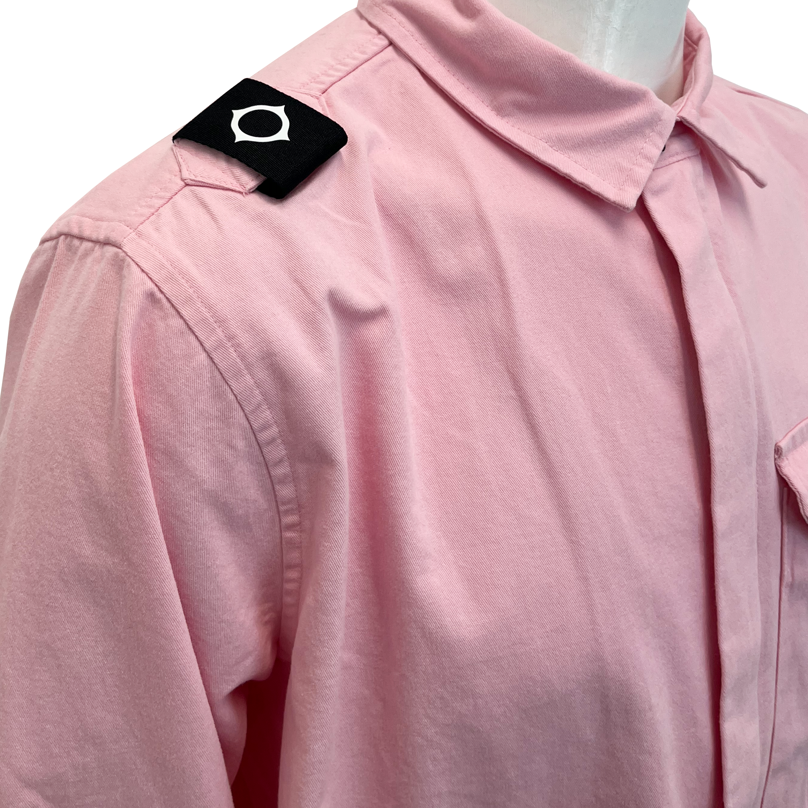 A close-up of a light pink collared shirt on a mannequin, featuring a black shoulder tab with a white circular emblem. MA.Strum Shirt Jacket available at Sakks Menswear in Southampton.