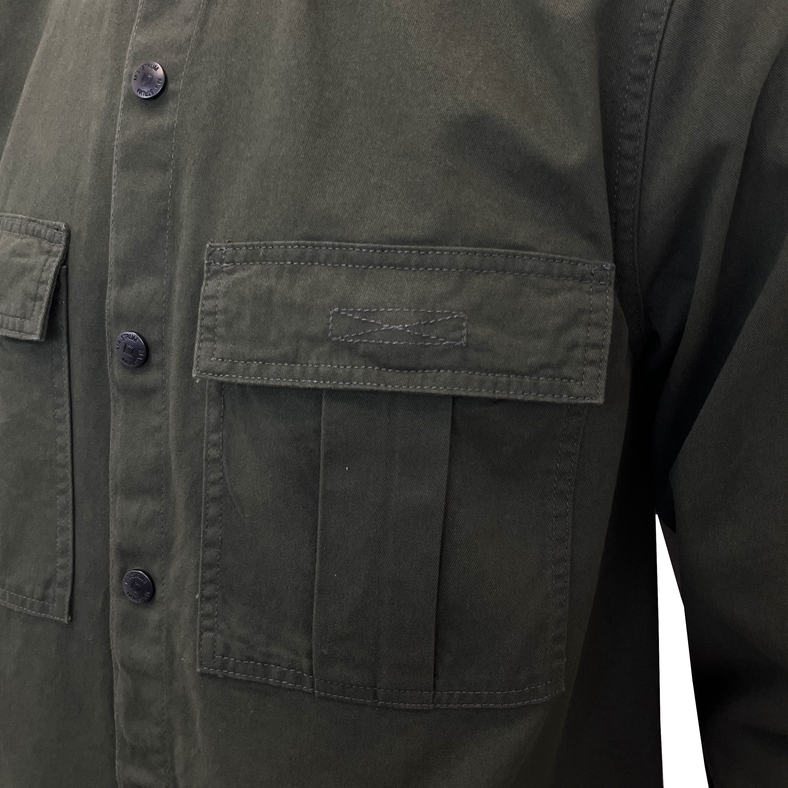 Close-up of an olive green utility jacket with a buttoned front and a large chest pocket. MA.Strum Shirt Jacket available at Sakks Menswear in Southampton.
