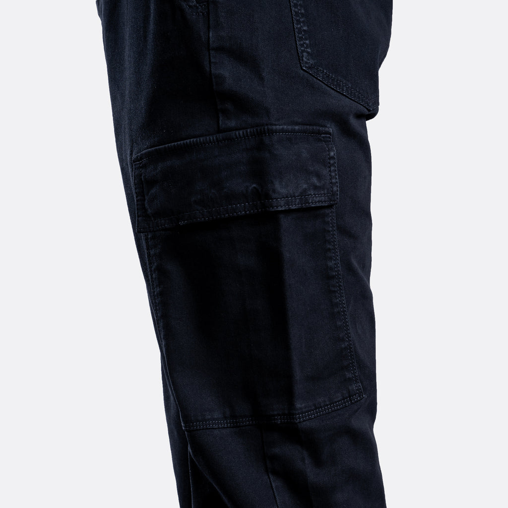 Close-up of dark navy cargo pants showing a large flap cargo pocket on the thigh, photographed against a light gray background. 7 For All Mankind Cargo Pants available at Sakks Menswear in Southampton.