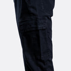 Close-up of dark navy cargo pants showing a large flap cargo pocket on the thigh, photographed against a light gray background. 7 For All Mankind Cargo Pants available at Sakks Menswear in Southampton.