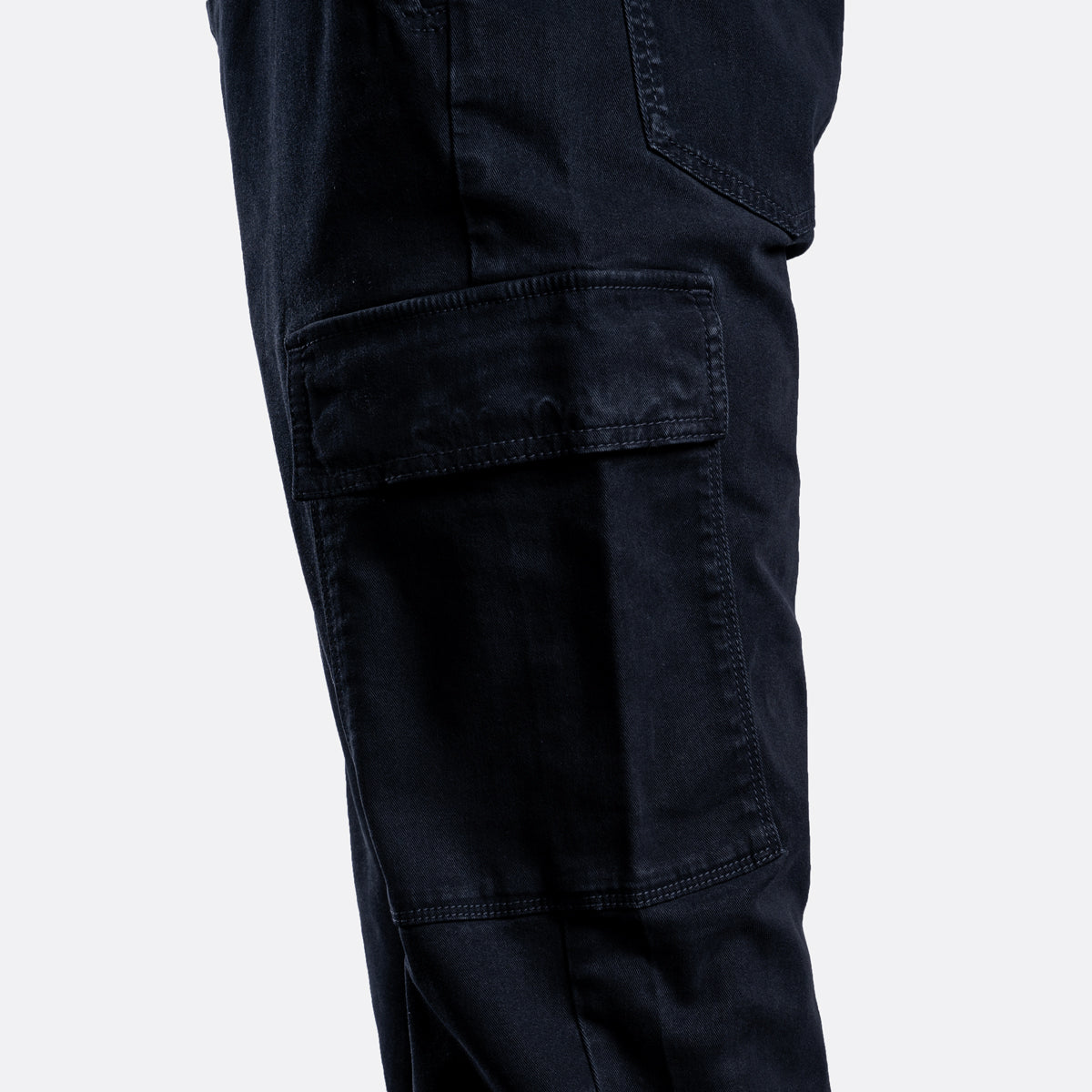 Close-up of dark navy cargo pants showing a large flap cargo pocket on the thigh, photographed against a light gray background. 7 For All Mankind Cargo Pants available at Sakks Menswear in Southampton.