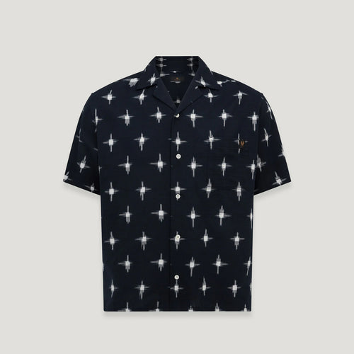 A short-sleeve button-up camp shirt in navy blue with a repeating white starburst pattern and a small embroidered logo on the chest pocket, shown against a light gray background. Belstaff Short Sleeve Shirt. Sakks Menswear Southampton.