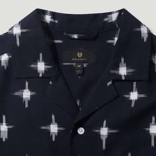 Close-up of a navy blue short-sleeve button-up shirt with a white ikat-style geometric pattern, featuring a pointed collar and a visible BELSTAFF brand label. Belstaff Short Sleeve Shirt. Sakks Menswear Southampton.