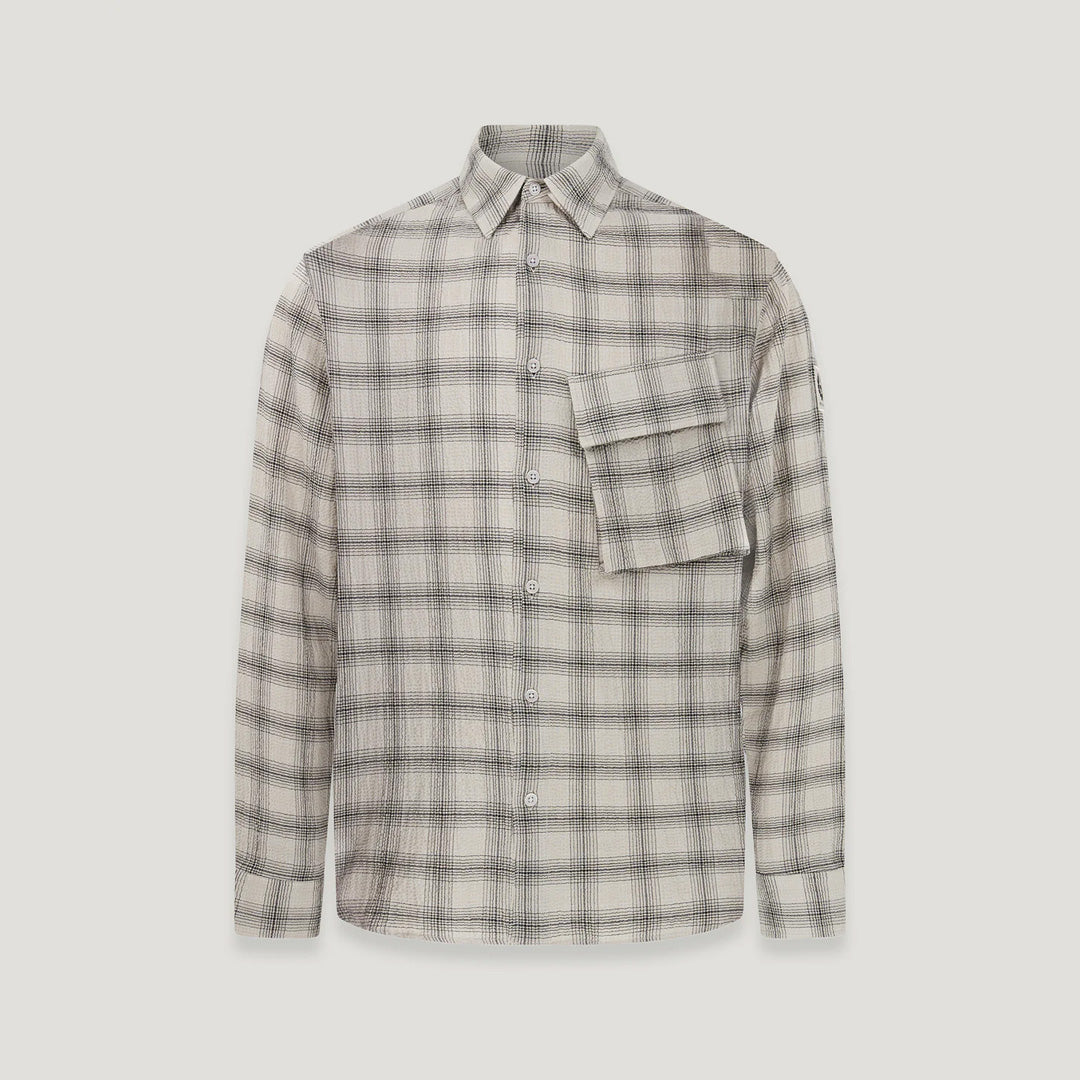 A long-sleeve button-up plaid shirt in beige, gray, and white, featuring a chest pocket and a small sleeve patch, shown against a light gray background. Belstaff Shirt. Sakks Menswear Southampton.