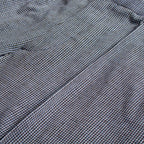 Close-up of a textured woven fabric with a fine micro-check pattern in gray, black, and subtle blue tones. Circolo 1901 Trousers available at Sakks Menswear in Southampton.