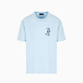 A light blue short-sleeve crewneck t-shirt with a small black seahorse graphic on the left chest, displayed on a clean white background. Emporio Armani T-Shirt. Sakks Menswear Southampton.