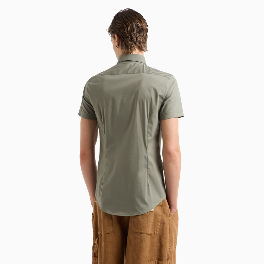 A man viewed from the back wearing a short-sleeve olive green button-up shirt and brown pants, set against a plain white background. Emporio Armani Short Sleeved Shirt. Sakks Menswear Southampton.