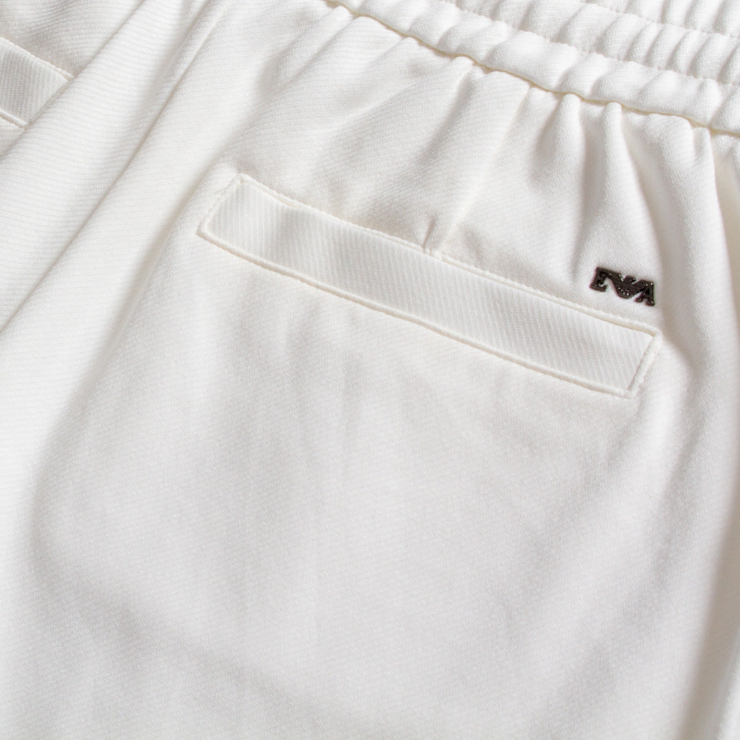 Close-up of white drawstring pants showing an elastic waistband, a side pocket, and a small black embroidered Emporio Armani logo. Emporio Armani Shorts. Sakks Menswear Southampton.