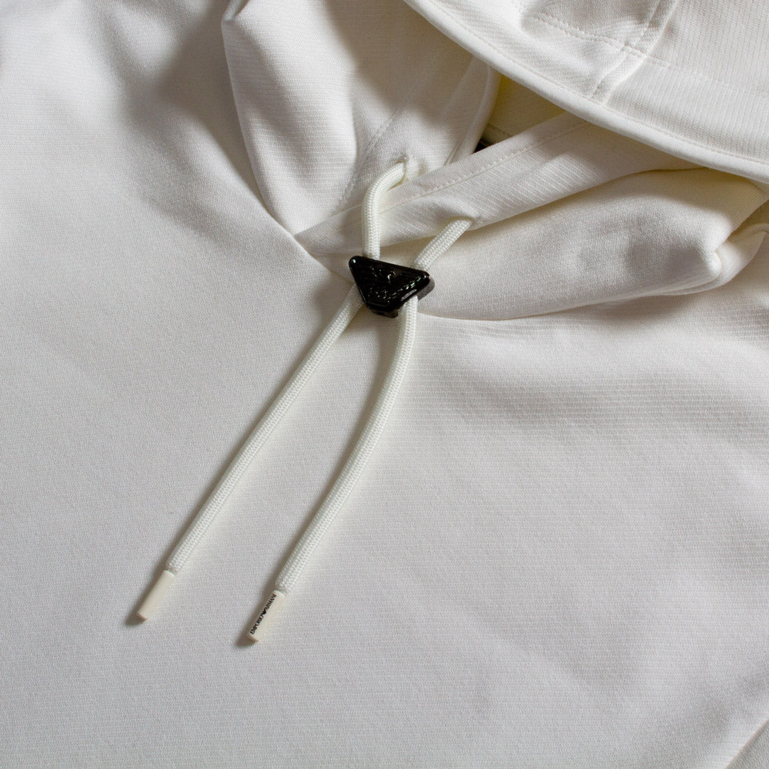 Close-up of a white hooded sweatshirt with white drawstrings and a small black triangular accent near the neckline. Emporio Armani Short Sleeved Hoodie. Sakks Menswear Southampton.