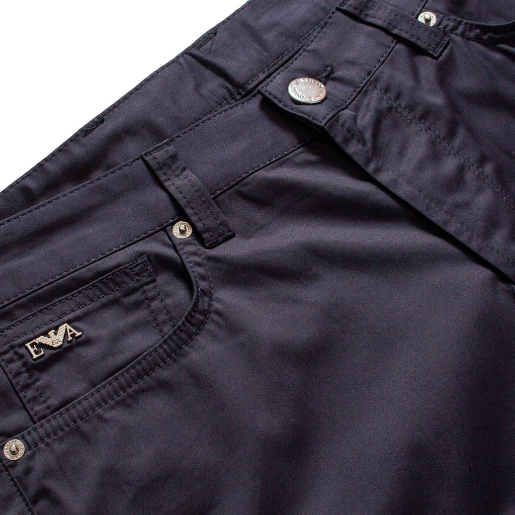 Close-up of dark navy pants showing the waistband, button closure, belt loop, front pocket, and a small embroidered logo on the pocket. Emporio Armani Shorts. Sakks Menswear Southampton.