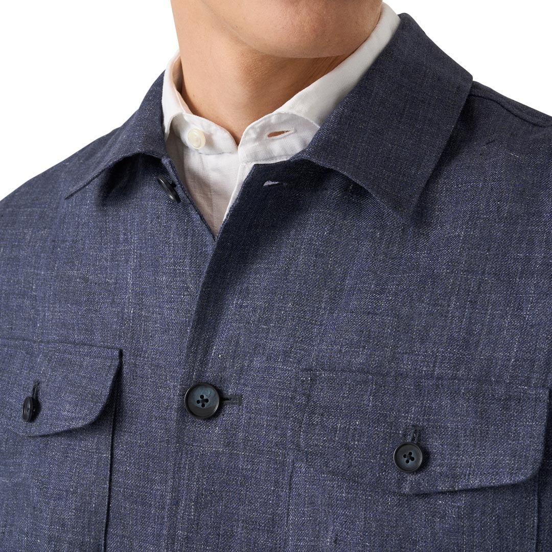 Close-up of a person wearing a textured navy blue overshirt over a white collared shirt, showing the collar, front buttons, and chest pockets. Eton Shirt Jacket available at Sakks Menswear in Southampton.