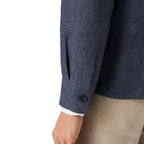 Close-up of a navy blue textured blazer sleeve with a button cuff, worn with beige trousers and a white dress shirt cuff visible, on a white background. Eton Shirt Jacket available at Sakks Menswear in Southampton.