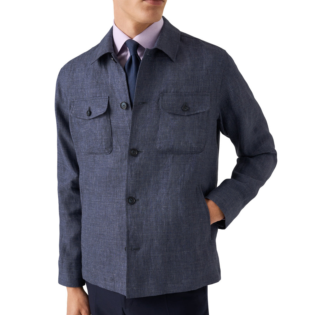 A man wearing a textured navy blue linen shirt jacket over a light purple dress shirt and a dark tie, shown from the chin down against a white background. Eton Shirt Jacket available at Sakks Menswear in Southampton.
