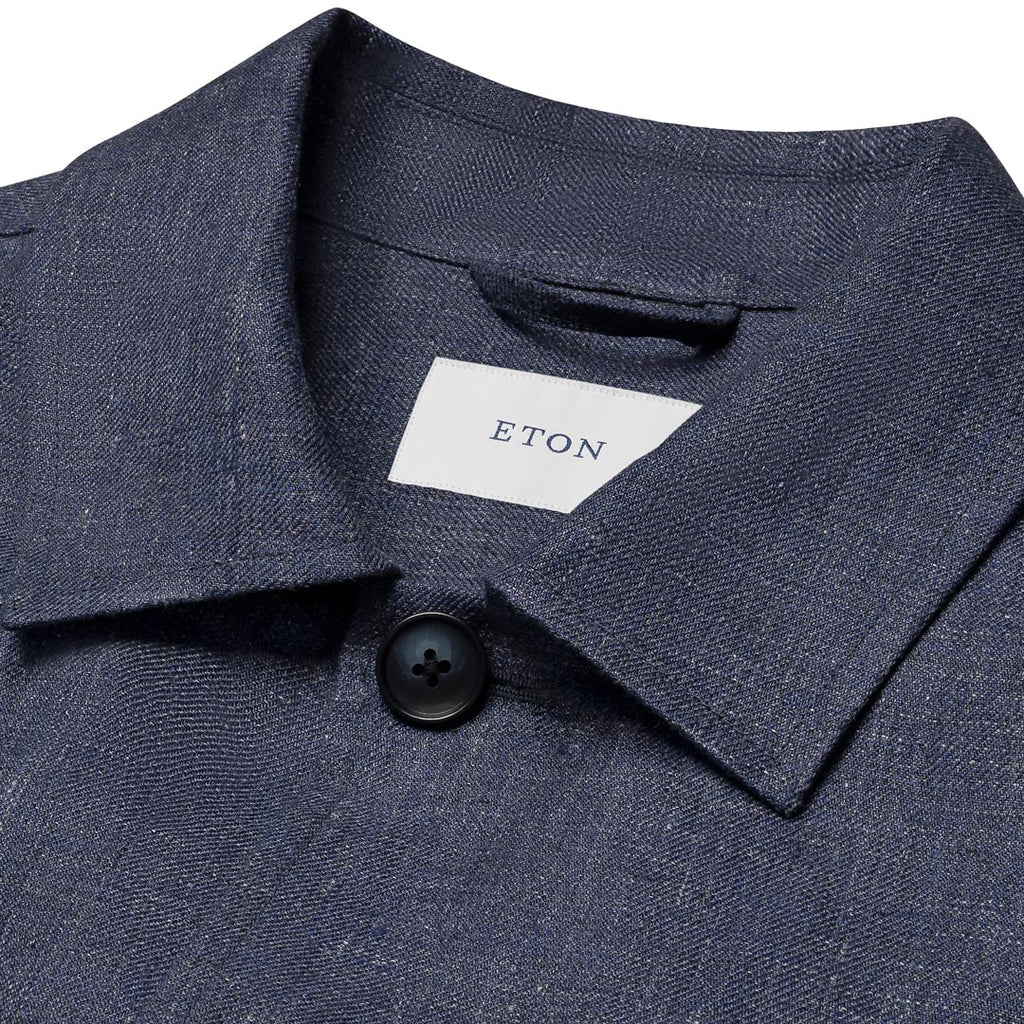 Close-up of a textured navy blue collared shirt with a white neck label reading ETON and a dark button, shown against a white background. Eton Shirt Jacket available at Sakks Menswear in Southampton.