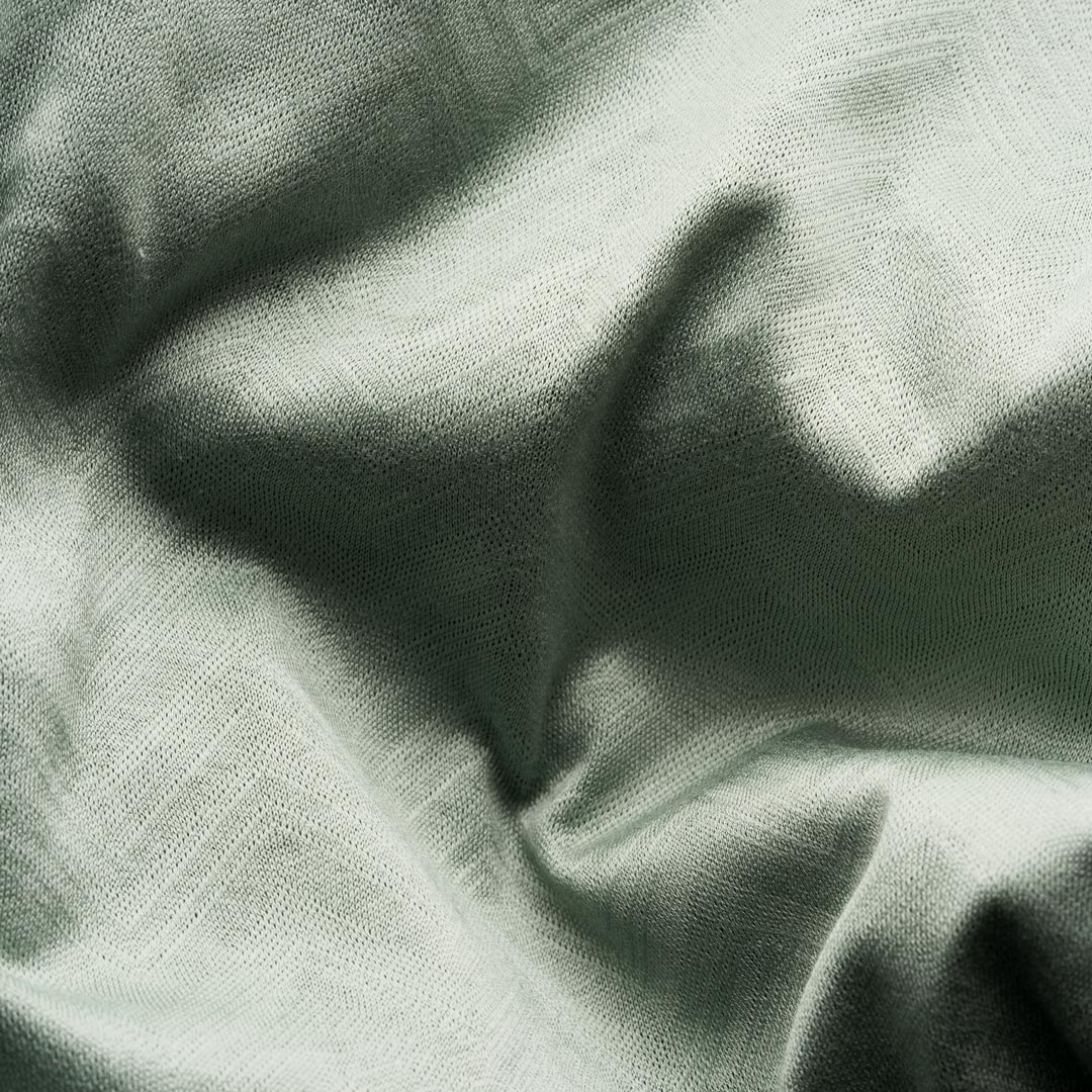 A close-up of draped sage green fabric with a visible woven texture and soft folds. Eton Short Sleeve Shirt available at Sakks Menswear in Southampton.