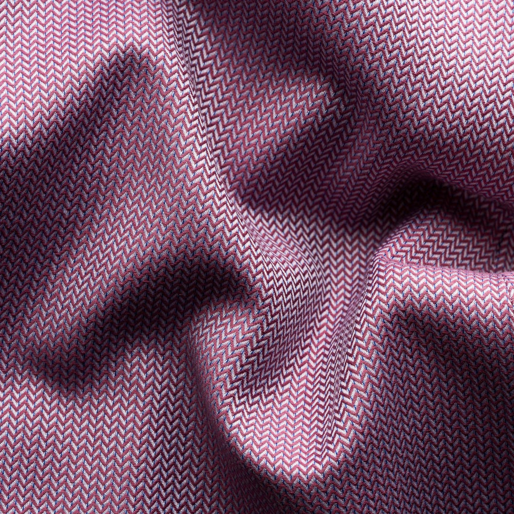 A close-up of draped fabric with a fine herringbone pattern in dusty purple and pink tones, showing soft folds and shadows. Eton Shirt available at Sakks Menswear in Southampton.