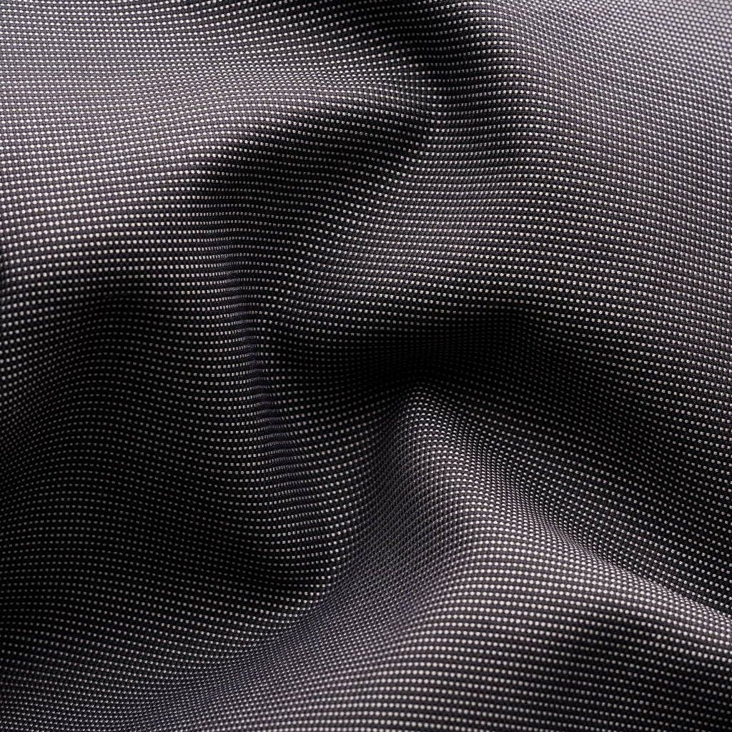 A close-up of a black fabric with a fine, repeating white dotted pattern, shown with soft folds and shadows. Eton Shirt available at Sakks Menswear in Southampton.