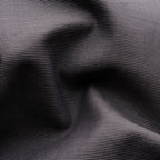 A close-up of a black fabric with a fine, repeating white dotted pattern, shown with soft folds and shadows. Eton Shirt available at Sakks Menswear in Southampton.
