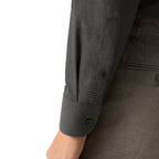 Close-up of a dark gray textured long-sleeve shirt with a buttoned cuff, worn with matching gray trousers against a white background. Eton Shirt available at Sakks Menswear in Southampton.