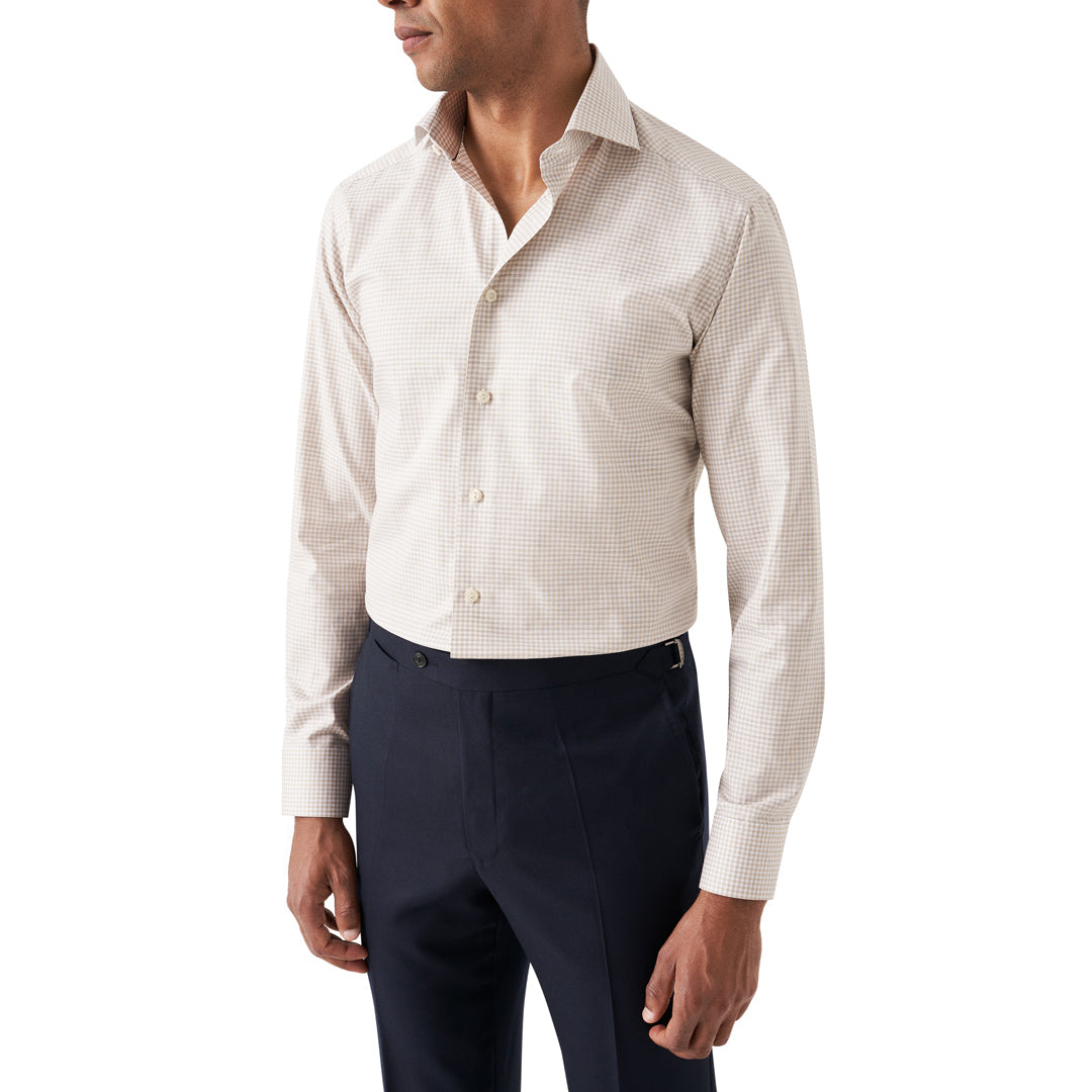A man wearing a light beige and white micro-check patterned long-sleeve dress shirt with dark navy trousers, shown from the side against a plain white background. Eton Shirt available at Sakks Menswear in Southampton.