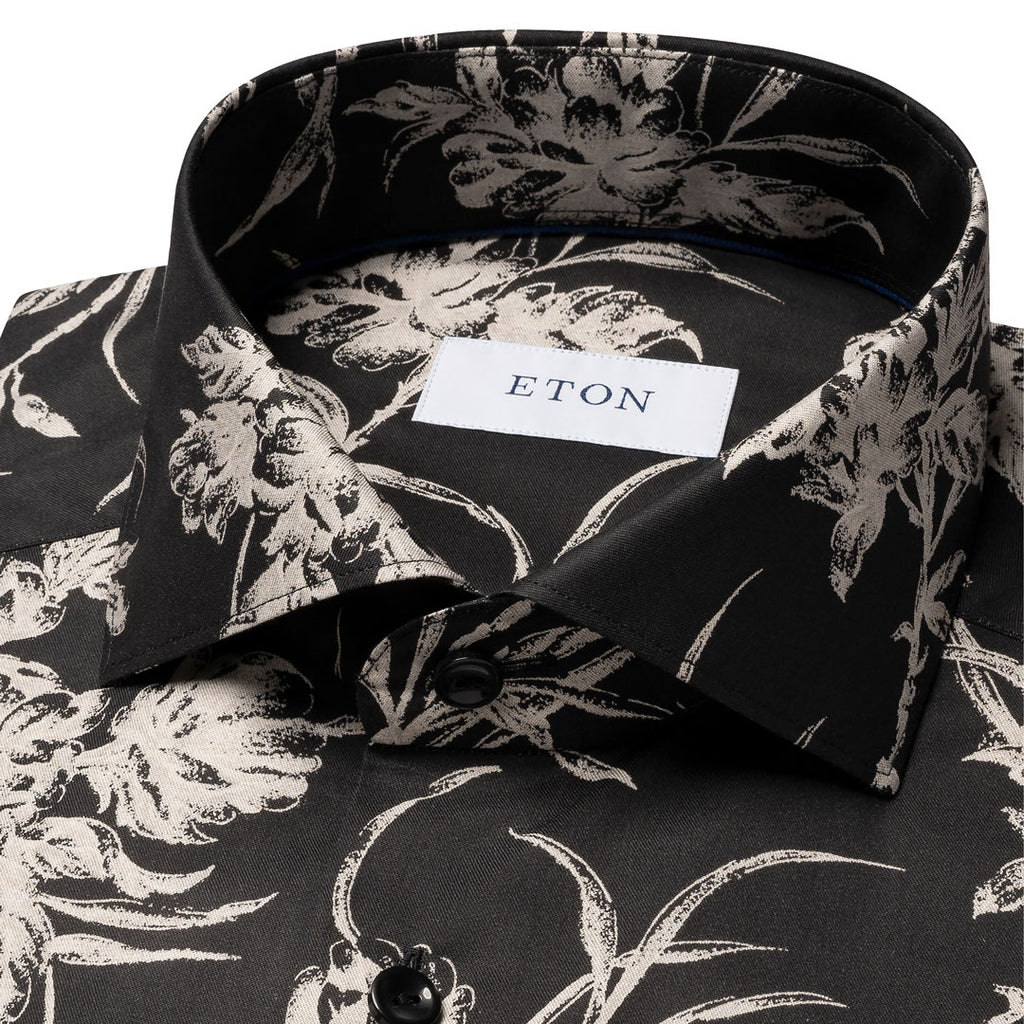 Close-up of a black dress shirt with a beige floral print, featuring a white neck label with the brand name ETON. Eton Shirt available at Sakks Menswear in Southampton.