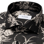 Close-up of a black dress shirt with a beige floral print, featuring a white neck label with the brand name ETON. Eton Shirt available at Sakks Menswear in Southampton.