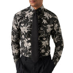 A man wearing a black long-sleeve dress shirt with a beige floral pattern, paired with a black tie and black trousers, shown from the chin down against a white background. Eton Shirt available at Sakks Menswear in Southampton.