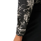 Close-up of a long-sleeve button-up shirt sleeve with a black base and white floral print, worn by a model with a black jacket or trousers visible underneath. Eton Shirt available at Sakks Menswear in Southampton.