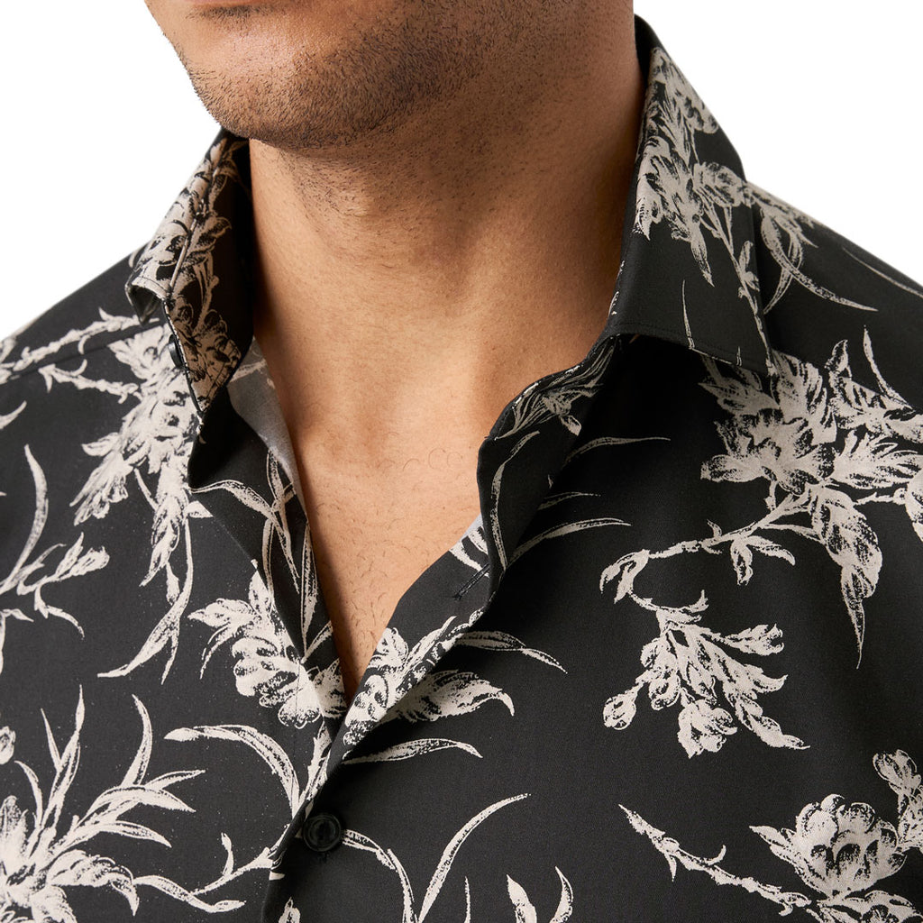 Close-up of a man wearing a black button-up shirt with a white floral and botanical print, showing the collar and chest area. Eton Shirt available at Sakks Menswear in Southampton.