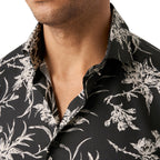 Close-up of a man wearing a black button-up shirt with a white floral and botanical print, showing the collar and chest area. Eton Shirt available at Sakks Menswear in Southampton.