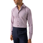 A man wearing a long-sleeve button-down dress shirt with fine horizontal stripes in pink and white, paired with navy trousers, shown against a plain white background. Eton Shirt available at Sakks Menswear in Southampton.