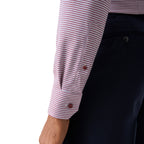Close-up of a person wearing a long-sleeve dress shirt with a fine pink and white houndstooth pattern, paired with dark navy trousers, against a plain white background. Eton Shirt available at Sakks Menswear in Southampton.