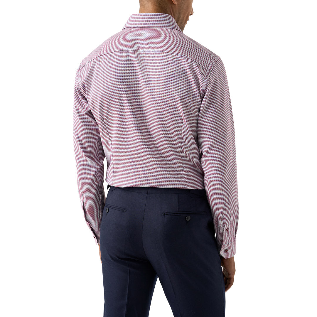 A man viewed from the back wearing a light pink and white striped long-sleeve dress shirt and navy blue trousers, against a plain white background. Eton Shirt available at Sakks Menswear in Southampton.