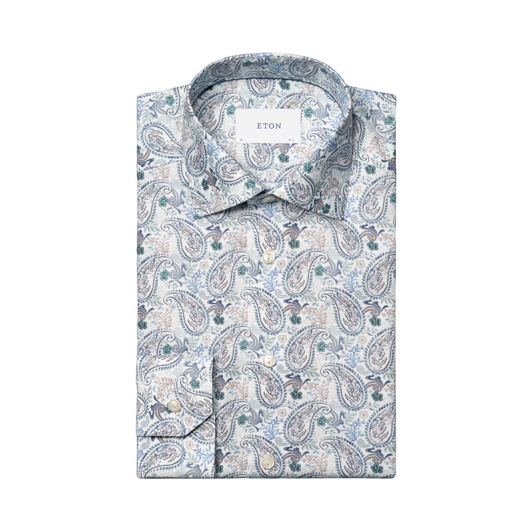 A folded men's dress shirt with a blue, gray, and beige paisley pattern, featuring a white neck label with the brand name ETON. Eton shirt available at Sakks Menswear in Southampton.