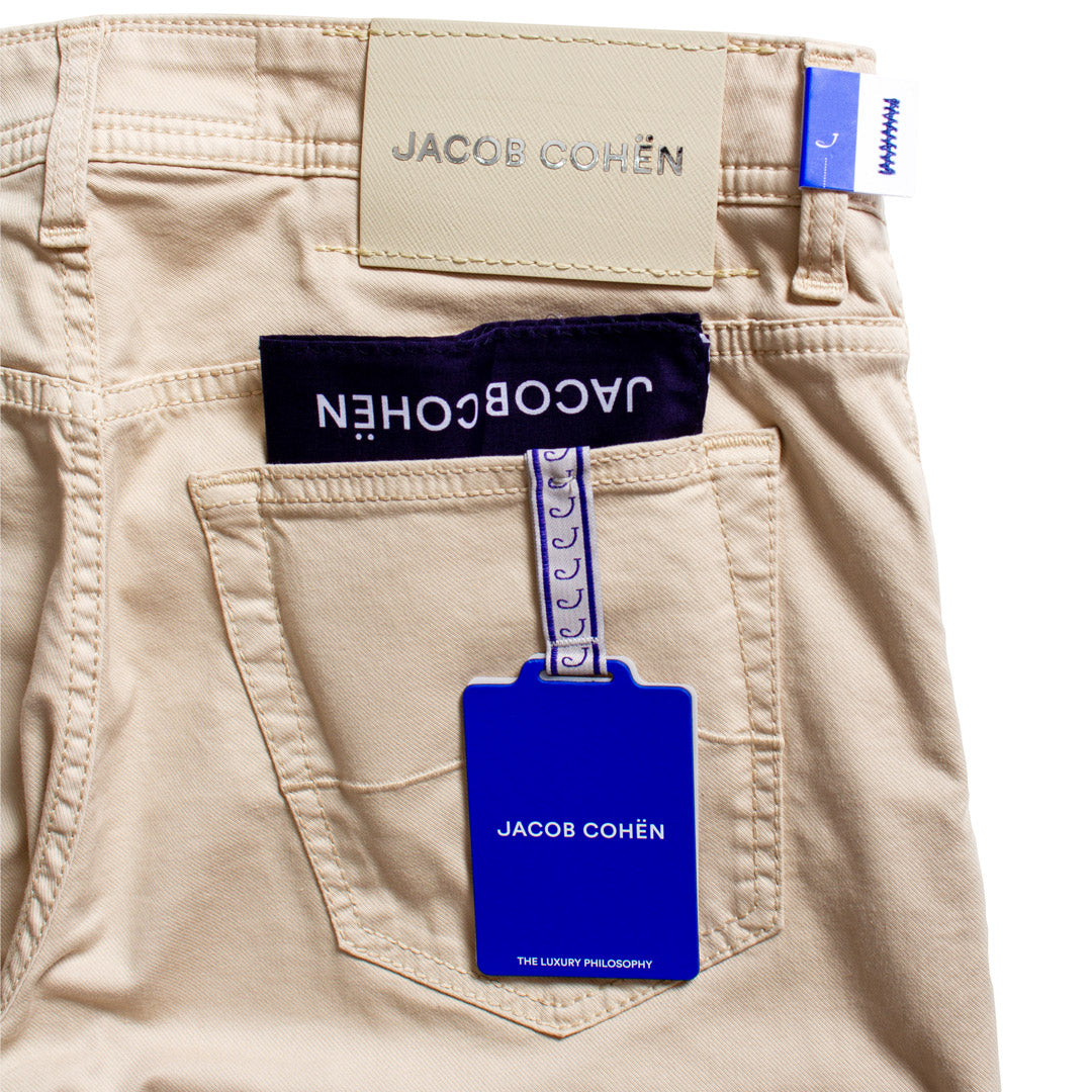 Close-up of the back pocket of beige chino pants with a blue Jacob Cohen hangtag attached, alongside the brand label and waistband tag. Jacob Cohën Chinos available at Sakks Menswear in Southampton.