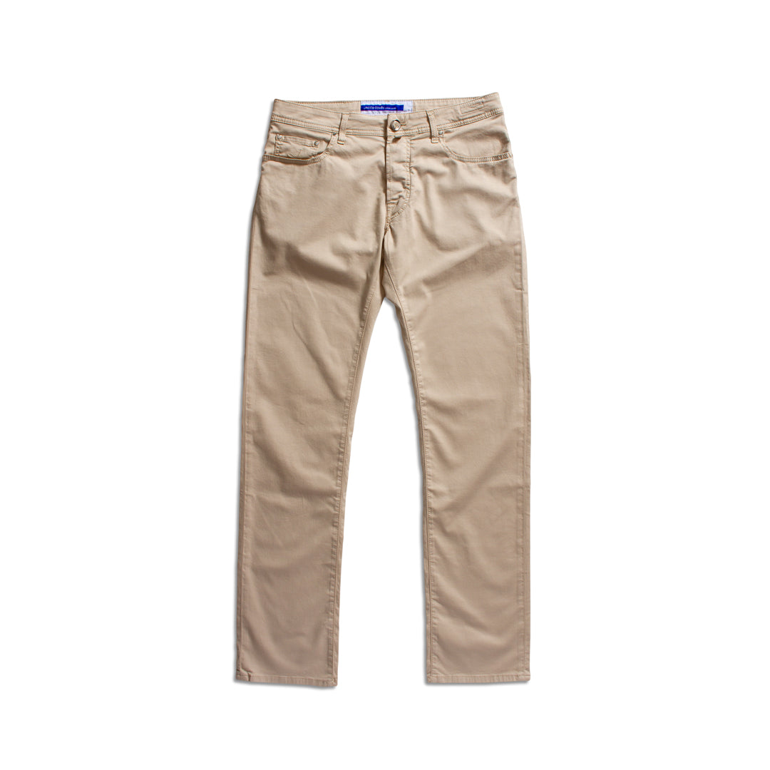 A pair of beige straight-leg jeans laid flat against a solid white background. Jacob Cohën Chinos available at Sakks Menswear in Southampton.
