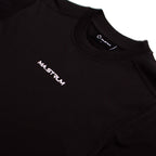 Close-up of a black crewneck sweatshirt with the brand name 'MA.STRUM' printed in white on the left chest and on the inner neck label. MA.Strum T-Shirt available at Sakks Menswear in Southampton.
