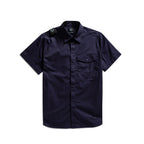 A dark navy blue short-sleeve button-up shirt with a chest pocket and shoulder epaulets, displayed flat against a white background. MA.Strum Short Sleeve Shirt available at Sakks Menswear in Southampton.