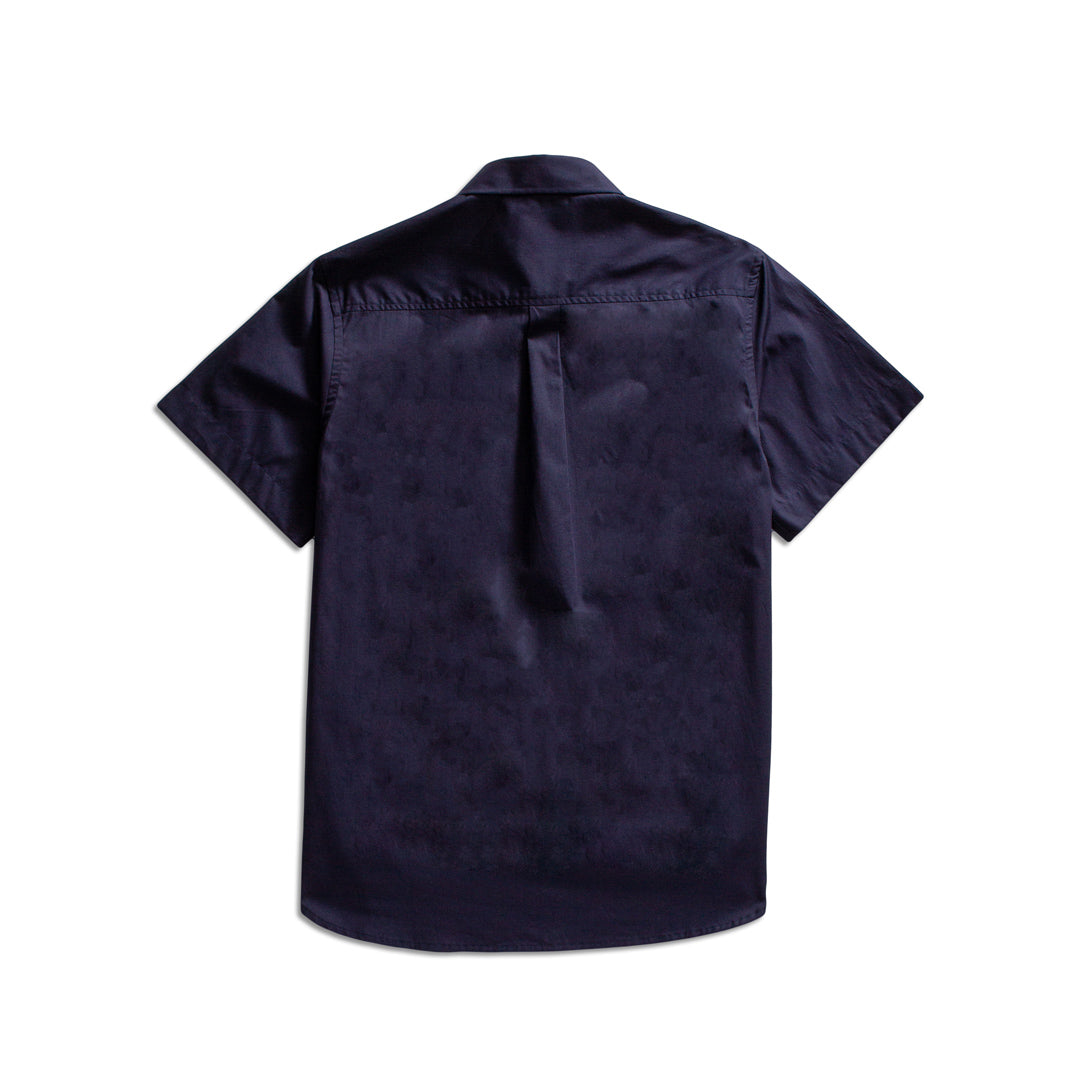 A dark navy blue short-sleeve button-up shirt shown from the back, featuring a subtle tonal textured pattern and a single button closure at the collar, photographed against a solid white background. MA.Strum Short Sleeve Shirt available at Sakks Menswear in Southampton.
