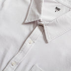 Close-up of a white button-down shirt collar with the brand name PAIGE printed inside the neck, showing white buttons and clean stitching. PAIGE Shirt available at Sakks Menswear in Southampton.