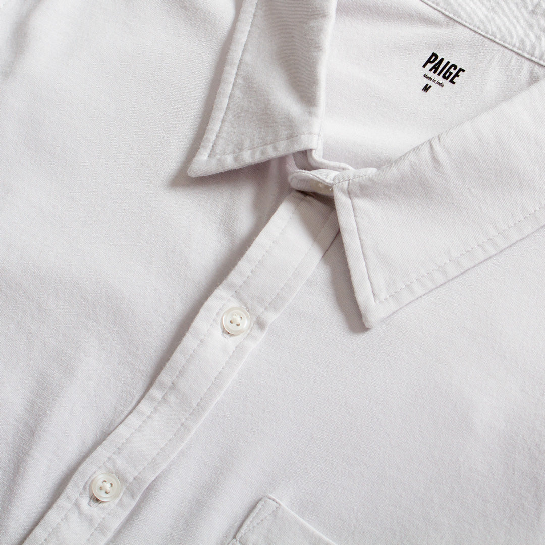 Close-up of a white button-down shirt collar with the brand name PAIGE printed inside the neck, showing white buttons and clean stitching. PAIGE Shirt available at Sakks Menswear in Southampton.