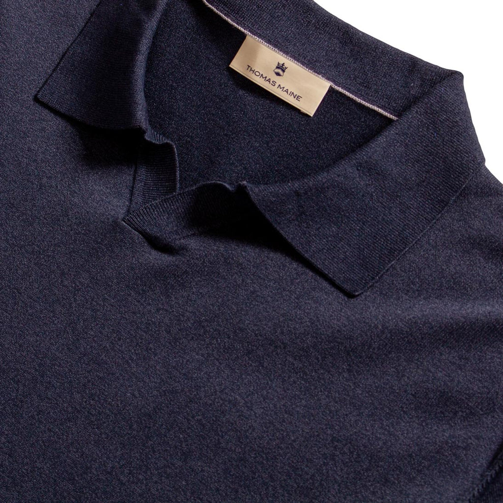 Close-up of a dark navy knit polo shirt collar with a beige Thomas Maine brand label visible inside the neck. Thomas Maine Polo available at Sakks Menswear in Southampton.