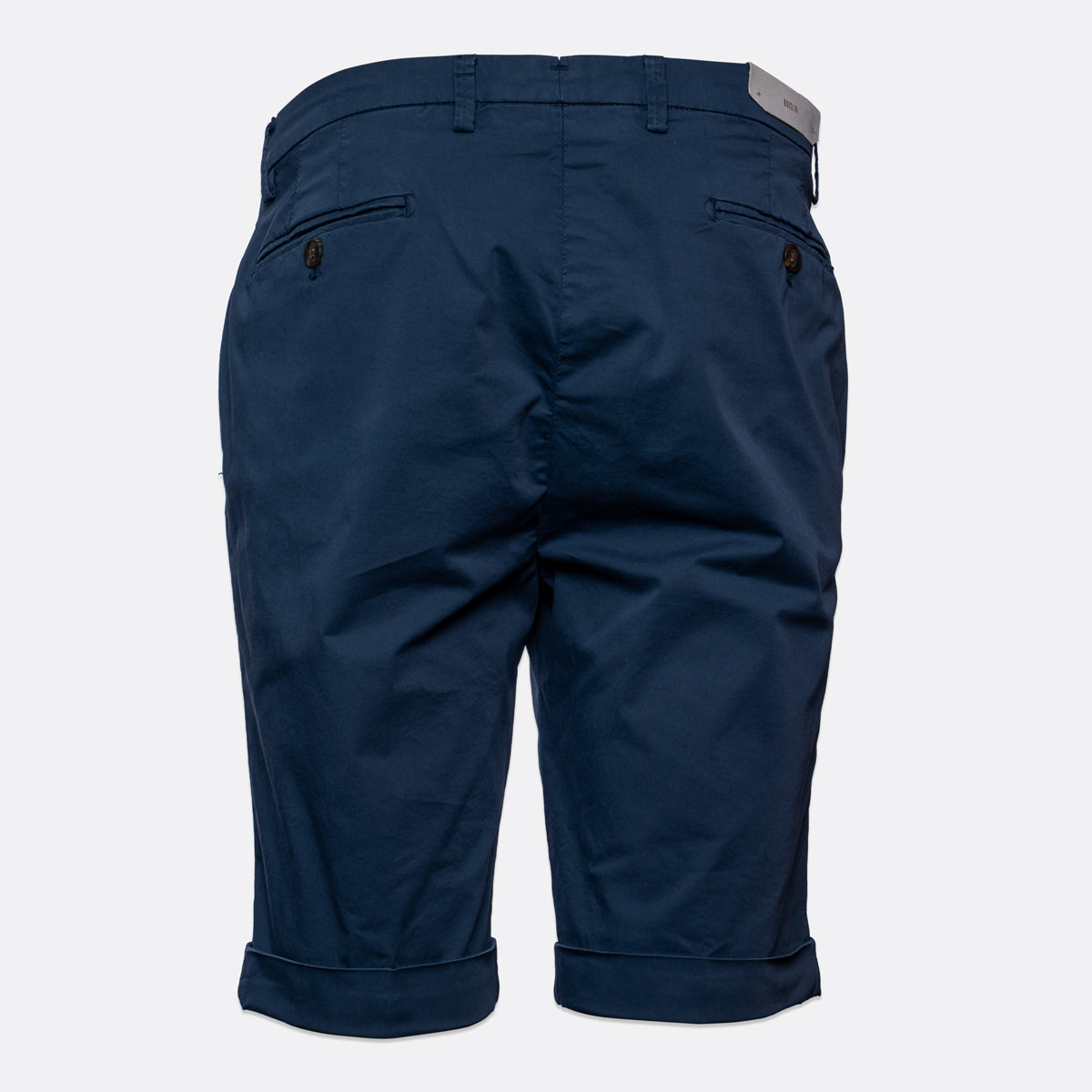 Back view of navy blue chino shorts with rolled cuffs and buttoned welt pockets, shown on a light grey background. Briglia Bermuda Shorts. Sakks Menswear Southampton.