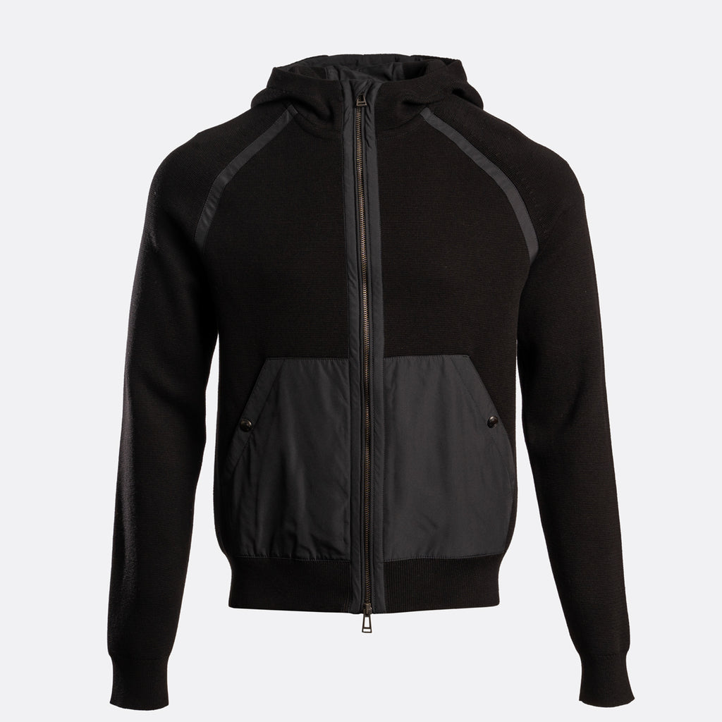 A black zip-up hooded jacket with contrasting dark gray front pockets and shoulder panels, shown on a light gray background. Belstaff Hoodie. Sakks Menswear Southampton.